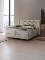 Ein luxuriöses Boxspringbett mit gestepptem Kopfteil und bequemer Matratze in einem modernen Schlafzimmer.