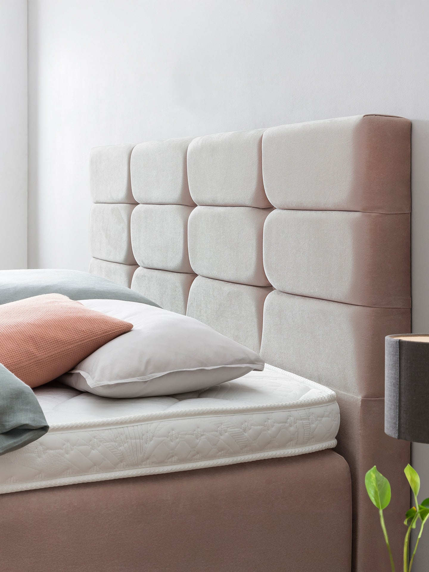 Nahaufnahme eines Bettes mit einem gepolsterten Kopfteil und Kissen in verschiedenen Farben.