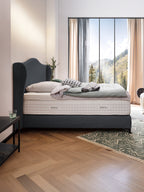 Ein Schlafzimmer mit einem BettCo Bett, einem Kopfteil in Anthrazit und einem Fenster mit Bergblick.