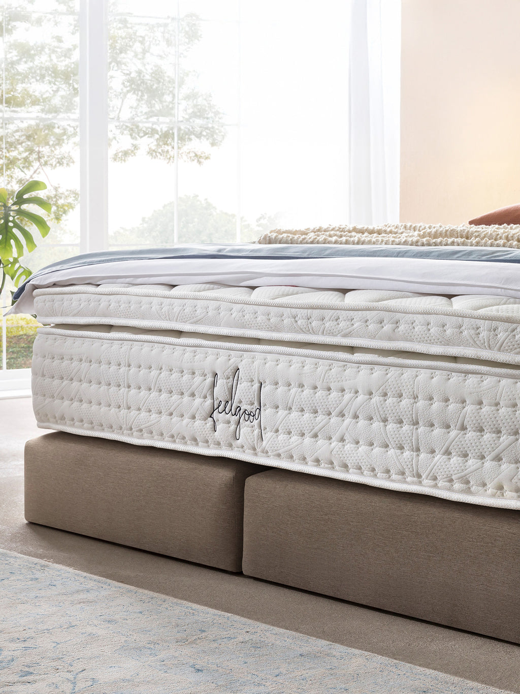 Nahaufnahme einer weißen Matratze mit dem Schriftzug feelgood in einem hellen Schlafzimmer.